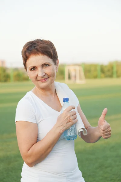 Donna sportiva 50 anni con una bottiglia d'acqua, all'aperto — Foto Stock