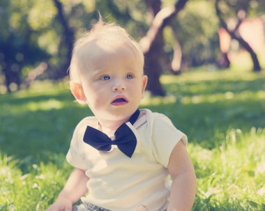 komik küçük çocuk parkta çimlere oturup...