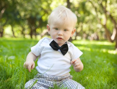 komik küçük çocuk parkta çimlere oturup...