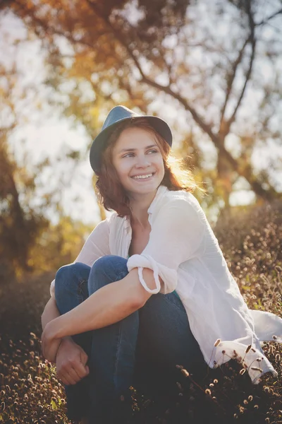 Bella ragazza seduta nel bagliore del sole al tramonto, a fuoco morbido — Foto Stock