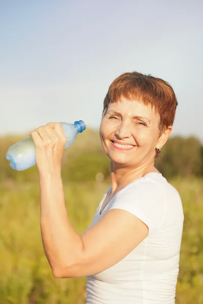 Femme sportive 50 ans avec une bouteille d'eau, en plein air — Photo