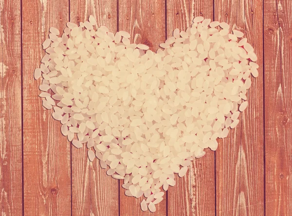 Grains de riz en forme de cœur sur un fond en bois — Photo