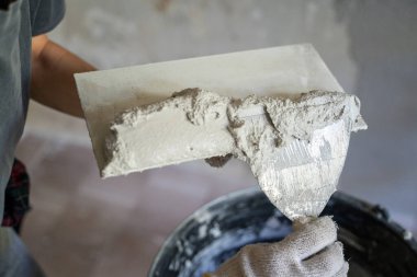 Eldivenli bir el malaya sıva ekler, yakın plan. Ev yenileme konsepti