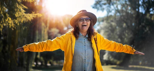Счастливая Взрослая Женщина Шляпе Желтой Куртке Наслаждающаяся Природой Парке Разводя — стоковое фото