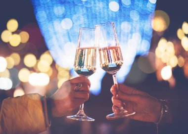 Gece sokaklarında şampanya kadehleriyle iki kadın eli Noel 'i ve yeni yılı kutluyor.