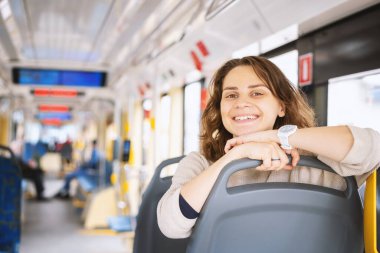 Çekici, mutlu, gülümseyen Avrupalı genç bayan öğrenci modern otobüste oturuyor.