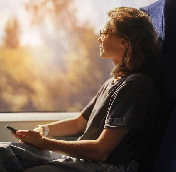 Νεαρή Γυναίκα Γυαλιά Κάθεται Ένα Τρένο Ένα Smartphone Στα Χέρια — Φωτογραφία Αρχείου