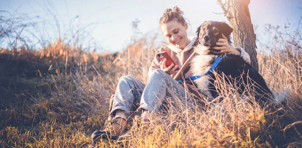 Vacker Glad Ung Kvinna Sitter Gräset Kramar Hund Med Smartphone — Stockfoto