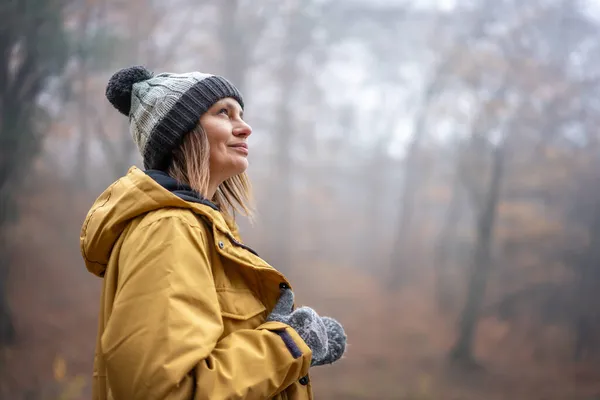 黄色い公園の魅力的な若い女性と秋の霧の森で新鮮な空気を楽しむ帽子 — ストック写真