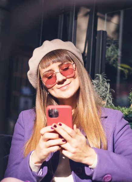 Young Happy Woman Purple Beret Coat Sunglasses Sitting Cafe Smartphone — Zdjęcie stockowe