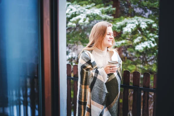 Young happy girl blonde woman on the balcony of her house enjoying snow hot tea overlooking the forest — Stock Photo, Image