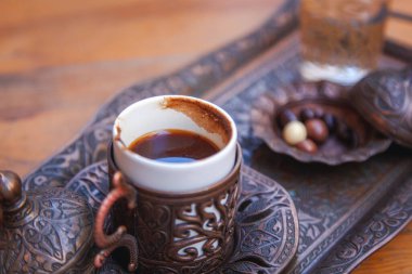 Turkish coffee in a half cup copper on a tray. View from above. Traditional Turkish drink with nuts in chocolate