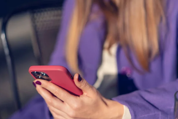 Woman Purple Coat Holds Red Smartphone Her Hands Close — Zdjęcie stockowe