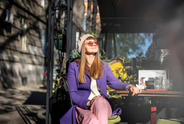 Young Cheerful Woman Purple Coat Sitting Street Cafe Enjoying Sunny — стоковое фото