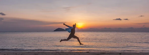 夕暮れ時に熱帯のビーチで喜びを持ってジャンプ若い男 — ストック写真