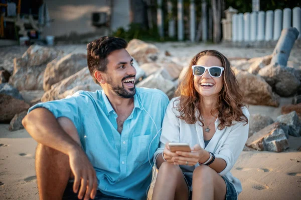 Happy Beautiful Young Couple Sitting Beach Sand Smartphone Laughing While — Stockfoto