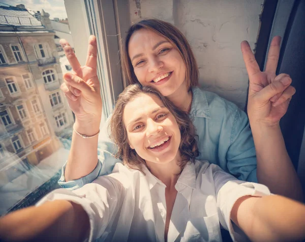 Young Beautiful Lesbian Couple Making Selfie Smartphone While Sitting Windowsill — Stock Photo, Image