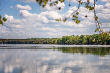 Beautiful summer landscape. River and green hills, clouds reflected in water