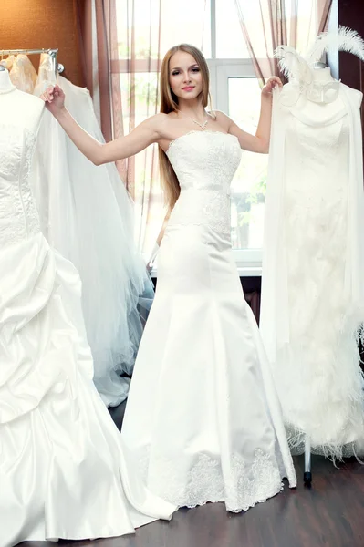 La mariée essayant des robes dans le salon de mariée — Photo