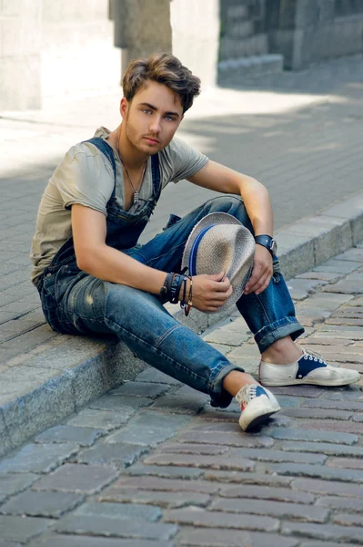 Young man sitting on the curb in the street — Stock Photo, Image