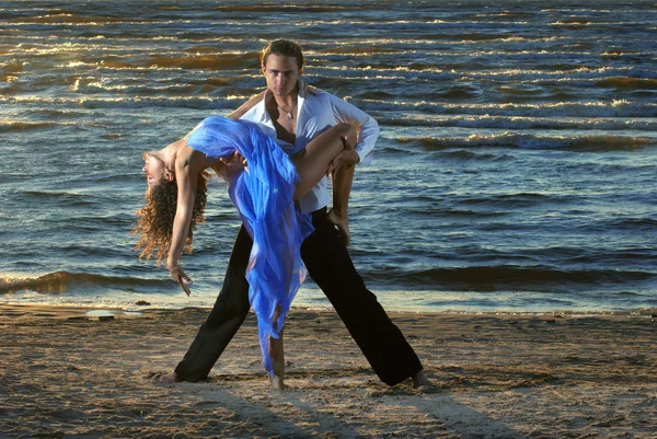 Beautiful couple dancing on the beach at the background of the sea — Stock Photo, Image