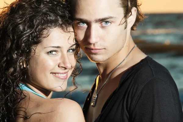 A young couple on the background of the sea at sunset, enjoying the weather — Stock Photo, Image