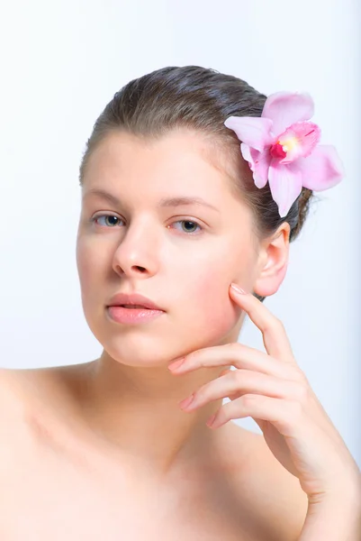 Vackra kvinnliga ansikte med frisk hud och blomma i håret i spasalong — Stockfoto