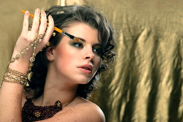 Mooi meisje met make-up houden kosmetische borstel — Stockfoto