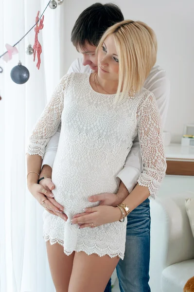 Těhotná žena se svým manželem doma na Vánoce — Stock fotografie