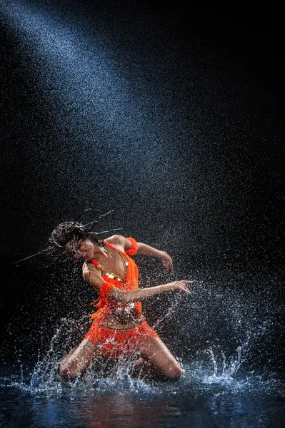 Kobietę tańczyć w deszczu w pomarańczowy strój. Studio — Zdjęcie stockowe