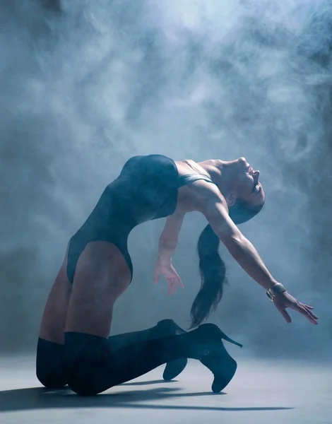 Modern style dancer posing on a studio grey background in fog — Stock Photo, Image