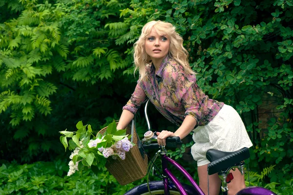 Vacker ung kvinna stående med cykel i parken. — Stockfoto