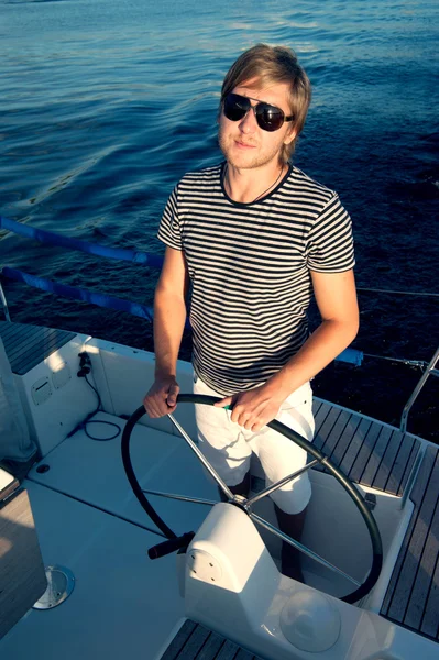 Heureux jeune homme tenant volant du yacht — Photo