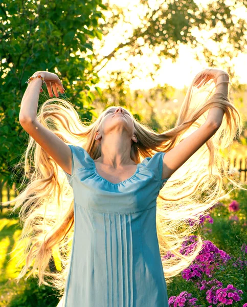 Vacker ung flicka med långa blonda hår i blå klänning på landsbygden — Stockfoto