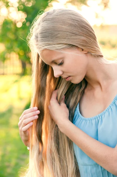 Porträt eines schönen jungen Mädchens mit langen blonden Haaren in blauem Kleid auf dem Land — Stockfoto