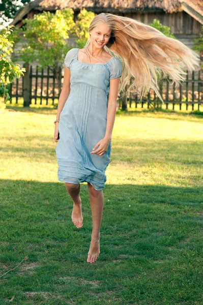 Hermosa joven con el pelo largo y rubio en vestido azul en el campo —  Fotos de Stock