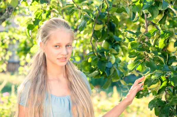 リンゴの木に近いポーズ美しいブロンドの女の子の屋外のポートレート — ストック写真