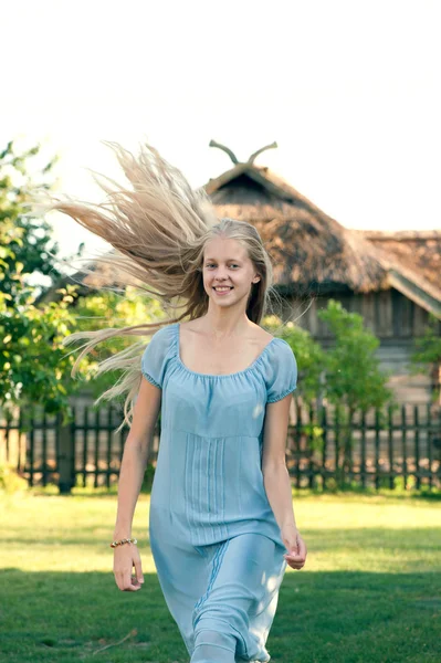 Piękna, młoda dziewczyna z długimi blond włosami w niebieska sukienka na wsi — Zdjęcie stockowe