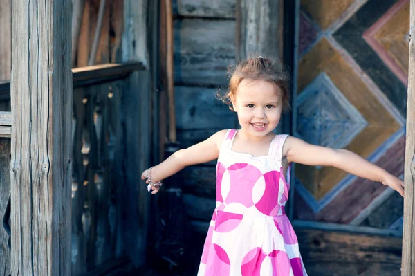 Young girl near an old wooden house — Stock Photo, Image