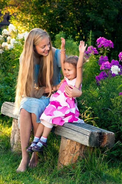 Beautiful blond young girl with her little sister in the countryside — Stock Photo, Image