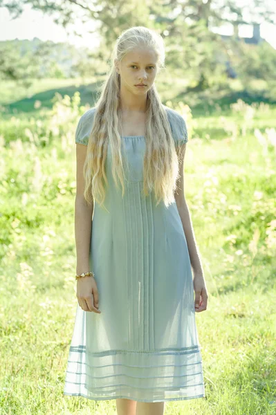 長いブロンドの髪と田舎で青いドレスで美しい少女 — ストック写真