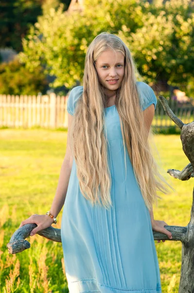 長いブロンドの髪と田舎で青いドレスで美しい少女 — ストック写真