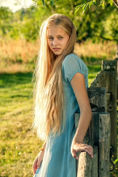 Beautiful young girl with long blond hair in blue dress in the countryside — Stock Photo, Image