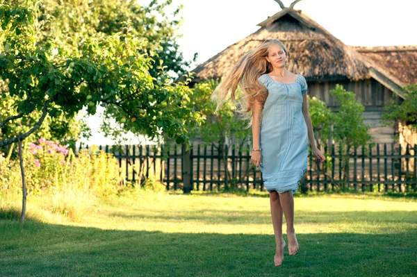 Hermosa joven con el pelo largo y rubio en vestido azul en el campo — Foto de Stock