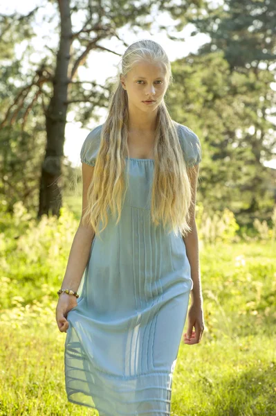 Belle jeune fille aux longs cheveux blonds en robe bleue à la campagne — Photo