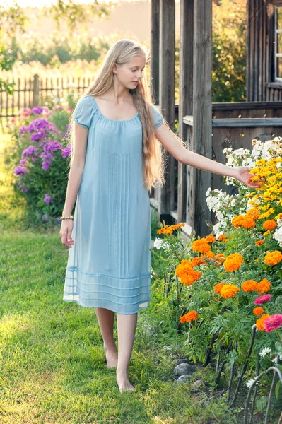 Schönes junges Mädchen mit langen blonden Haaren in blauem Kleid auf dem Land — Stockfoto