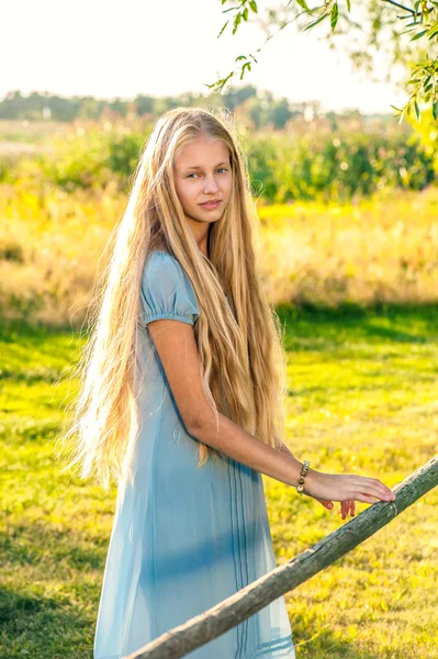 Belle jeune fille aux longs cheveux blonds en robe bleue à la campagne — Photo