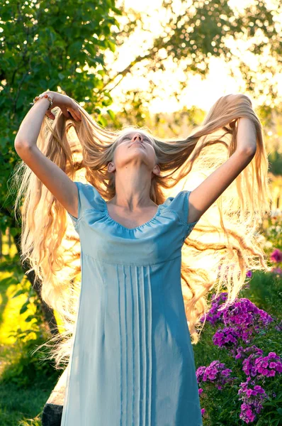 Beautiful young girl with long blond hair in blue dress in the countryside Stock Picture