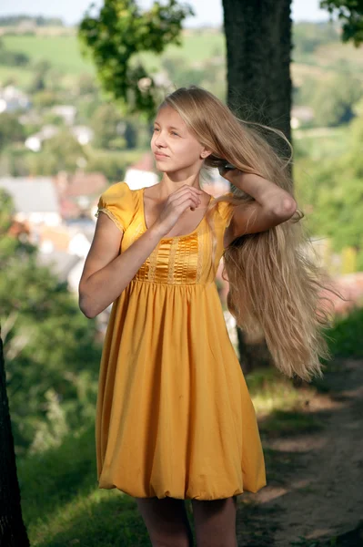 Chica en vestido amarillo contra el paisaje rural fondo —  Fotos de Stock