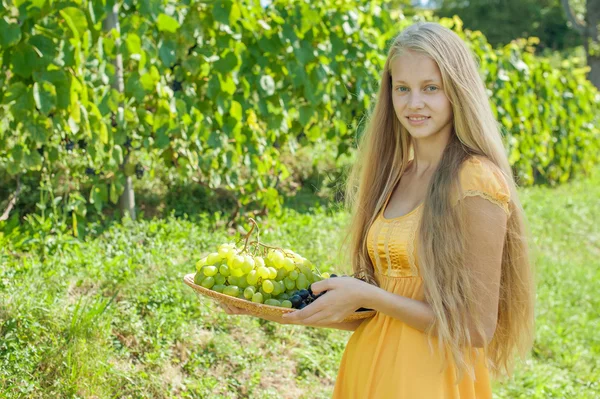 Portrait of a beautiful young blonde holding bowl of grapes — Stock Photo, Image